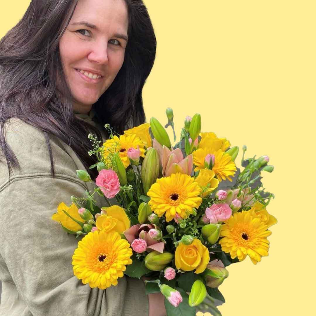 En av våre fantastiske kvinnelige ansatte som holder en bukett med gule krysantemum