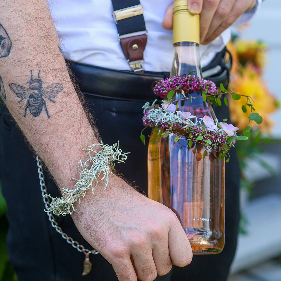 Blomsterpynt festet til flaske og armbånd laget av lyng