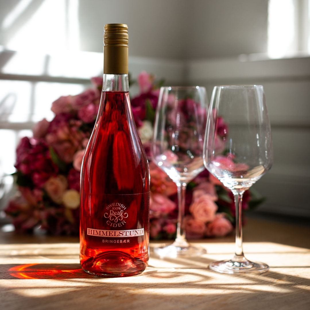Bringebærcider, rosa bukett og to glass